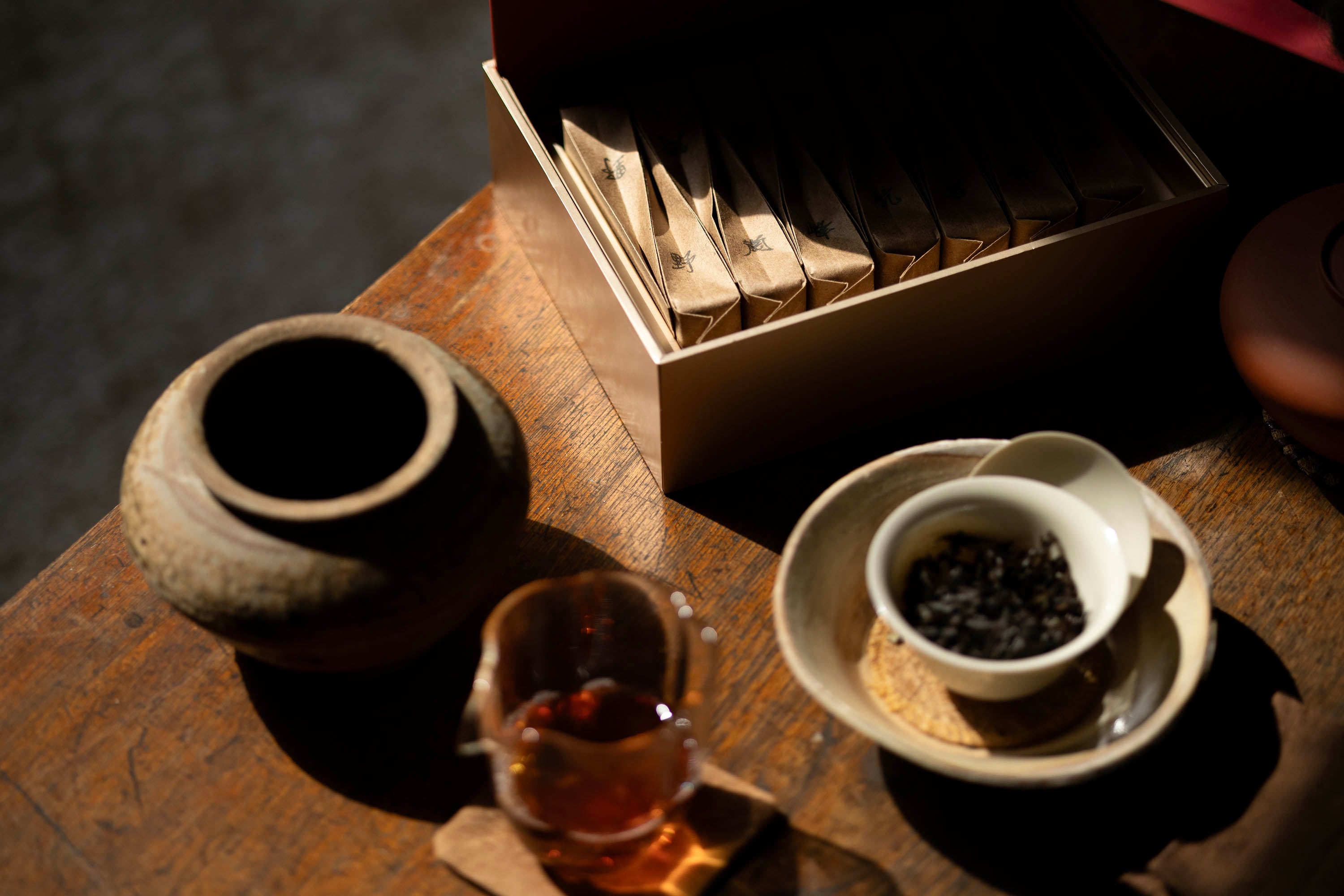 An open hyt Wuyi Yancha 2026 Horse Year wulong tea box next to a white gaiwan and glass tea pitcher on a wooden table.