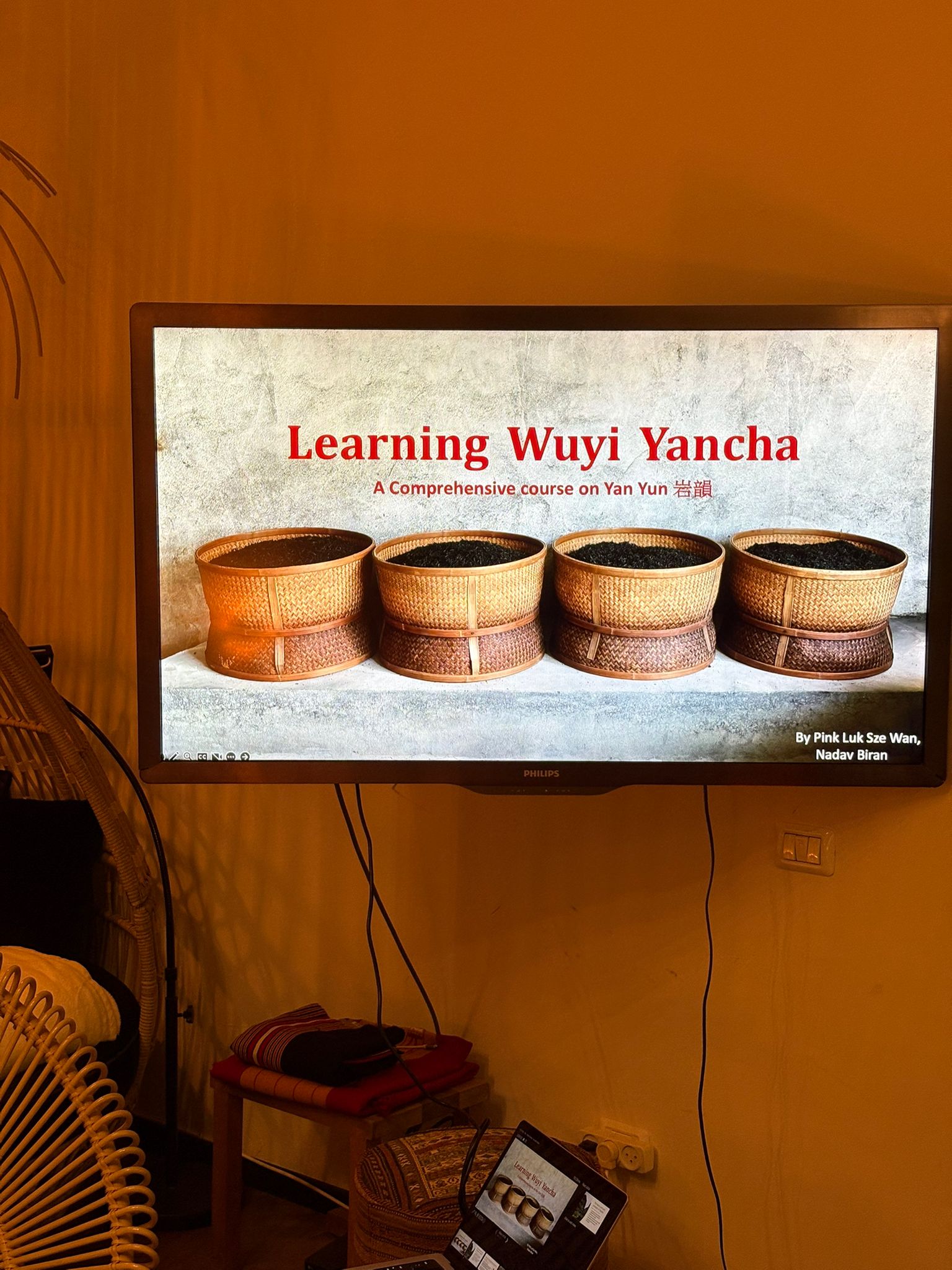 A TV screen displaying the title slide for the Learning Wuyi Yancha comprehensive course on Yan Yun, featuring four woven bamboo baskets of dark wulong tea.