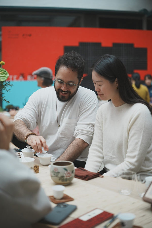A man and a woman brewing tea together at a tea event table