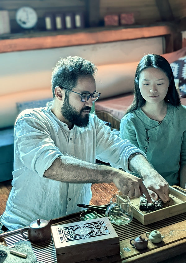 A man and a woman preparing gongfu tea at a tea table