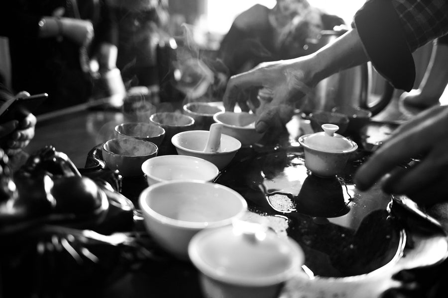 Hands gathered around a plate of fresh tea leaves
